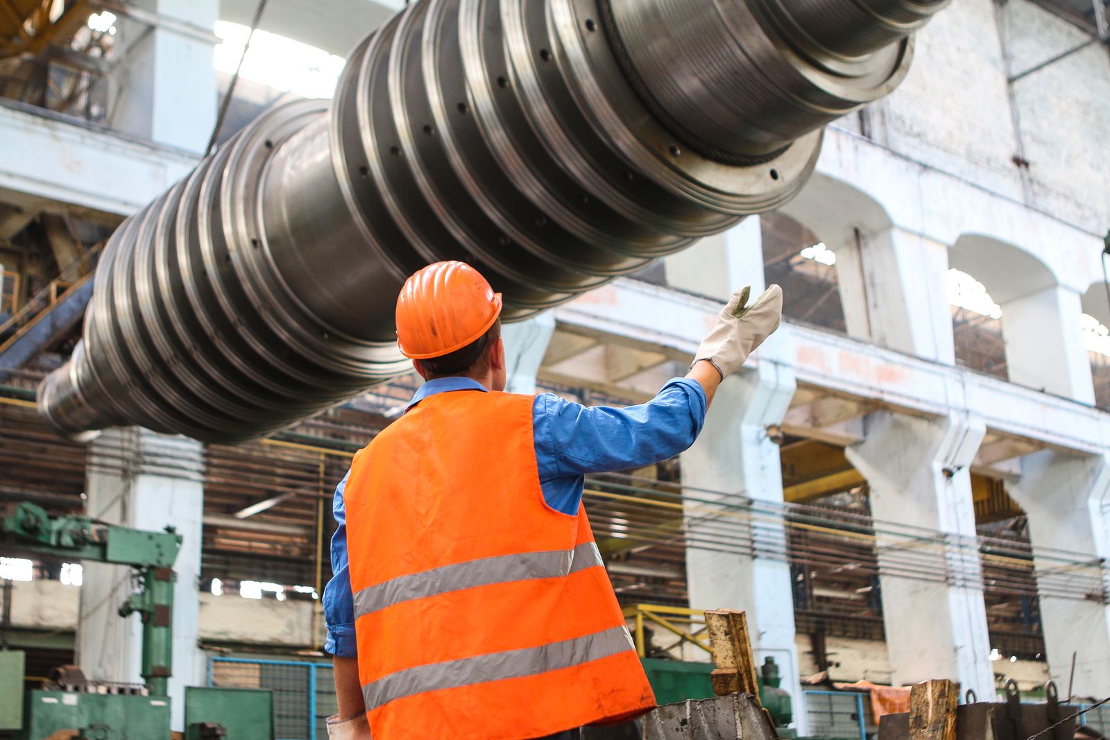 Persona con casco coordinando carga en un piso industrial; fotografía ilustrativa