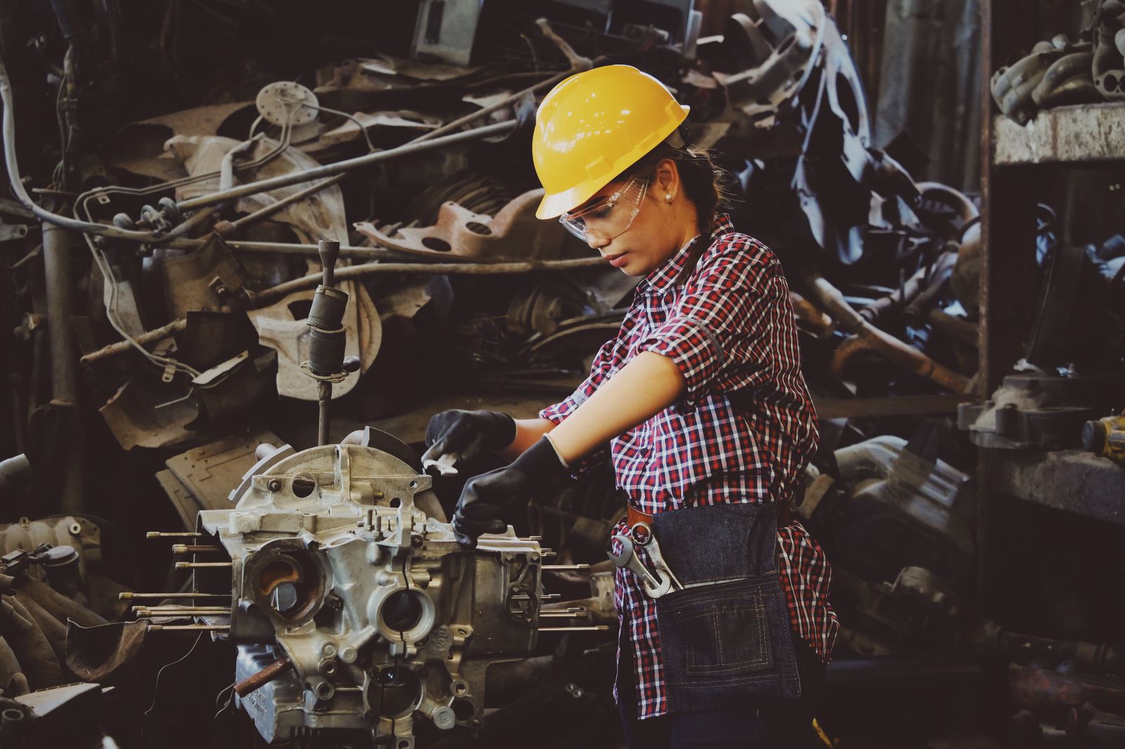 Persona con casco trabajando en un ensamble industrial; fotografía ilustrativa